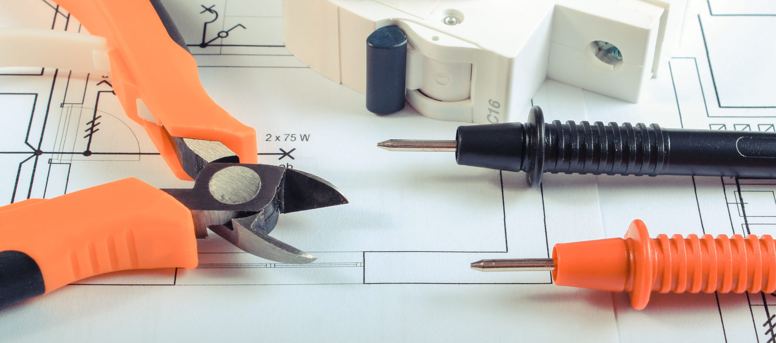 Cables of multimeter, metal pliers and electric fuse on construction drawing of house. Building home concept. Diagrams for projects engineer jobs